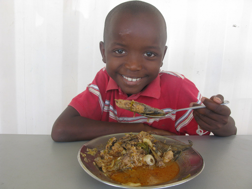 Ein Junge im nph-Kinderdorf genießt sein Mittagessen.