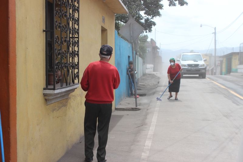 Anwohner reinigen die Strasse von Vulkanasche nach dem Vulkanausbuch in Guatemala.